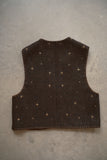 Brown vest with gold star patterns on a gray surface